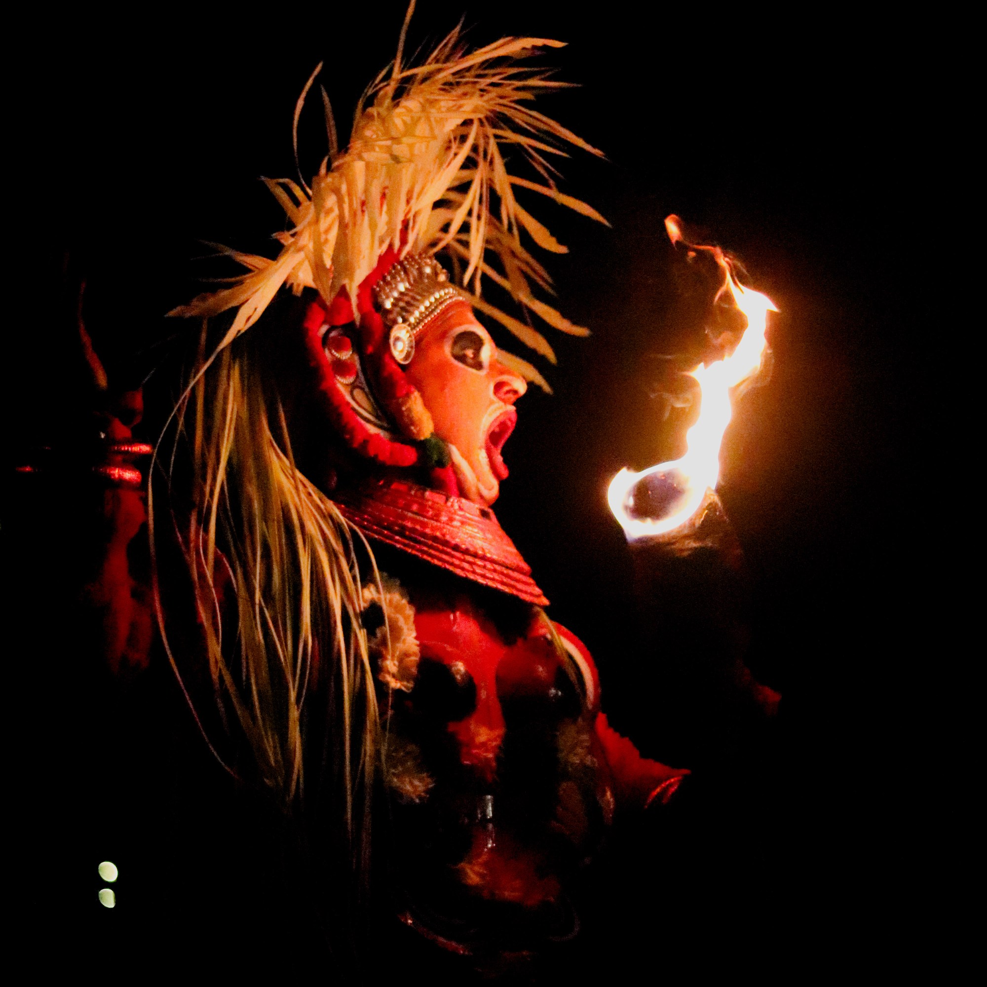 A Theyyam dancer blowing fire.